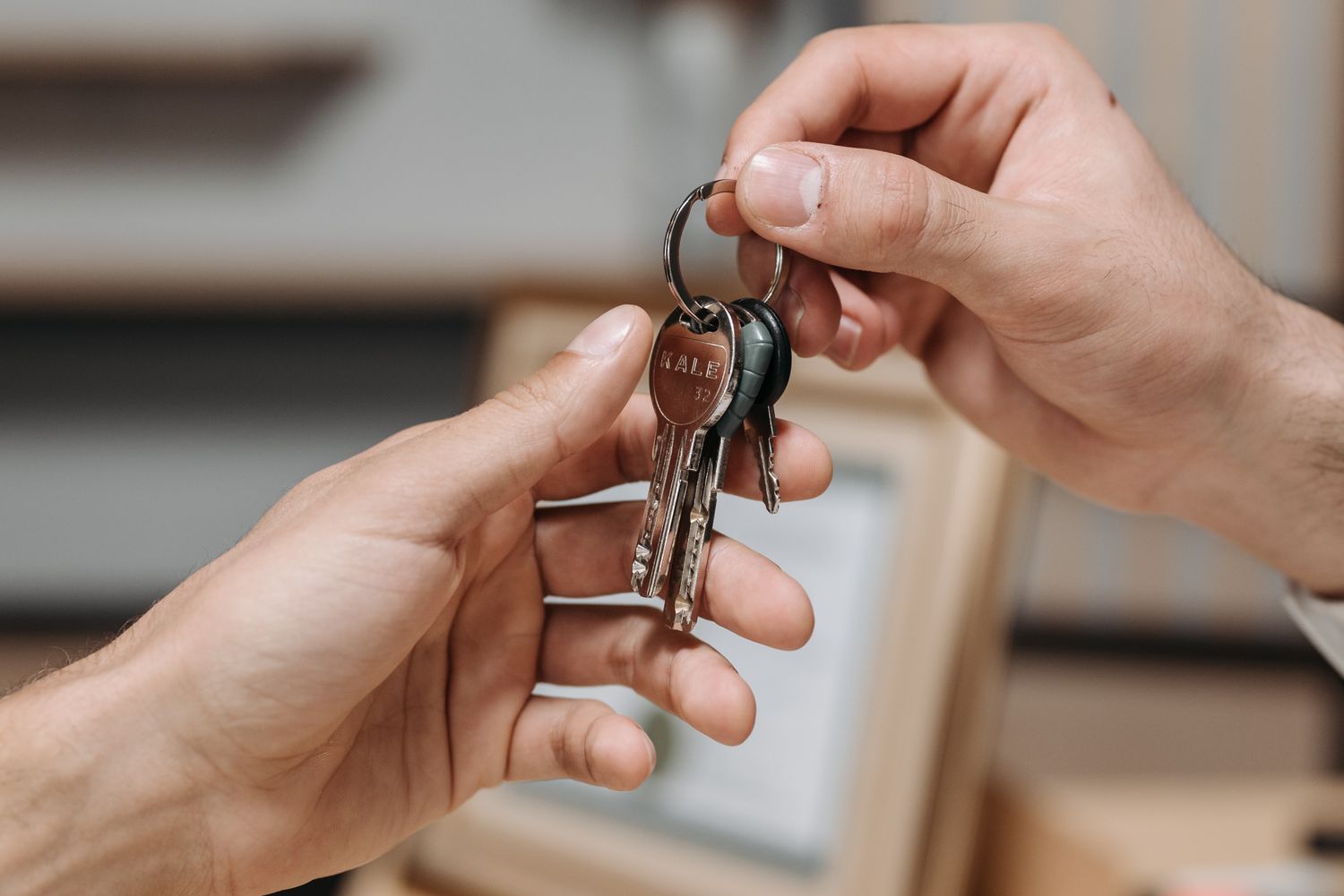 Two hands exchanging a set of keys indoors