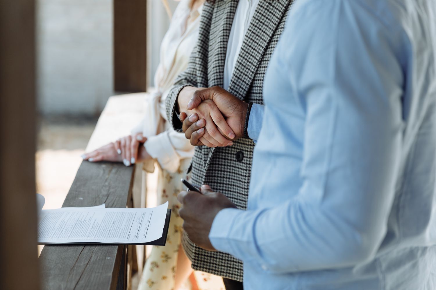 Two people shaking hands over a signed property agreement