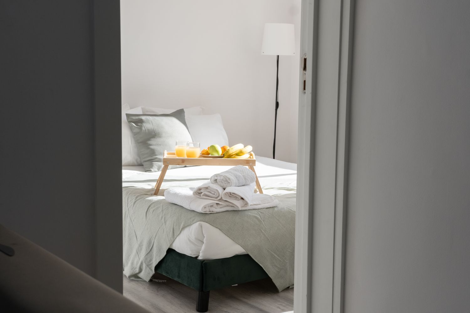 Guest-ready bedroom with fresh towels and a breakfast tray on the bed