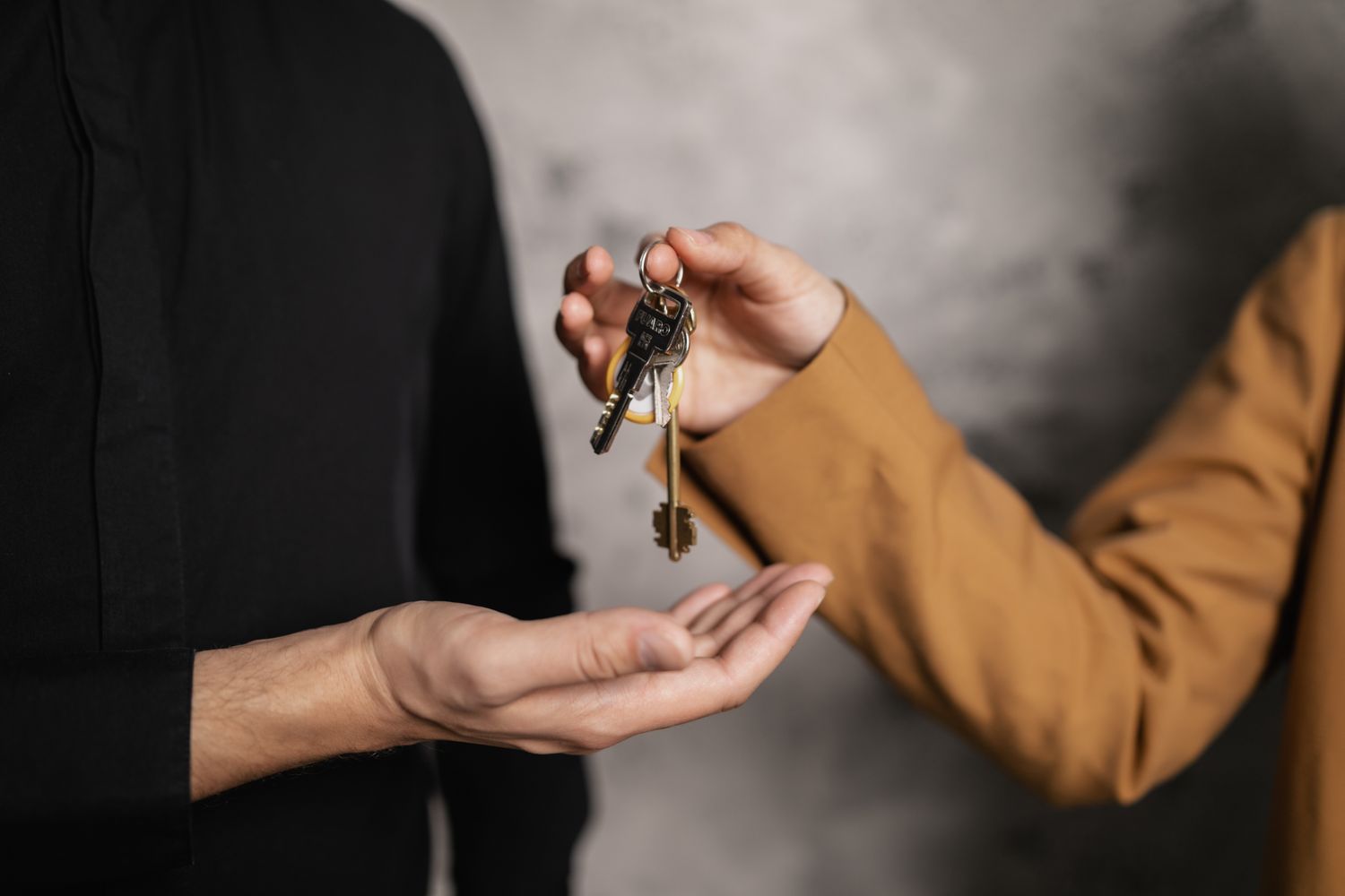 One person handing a bundle of house keys to another