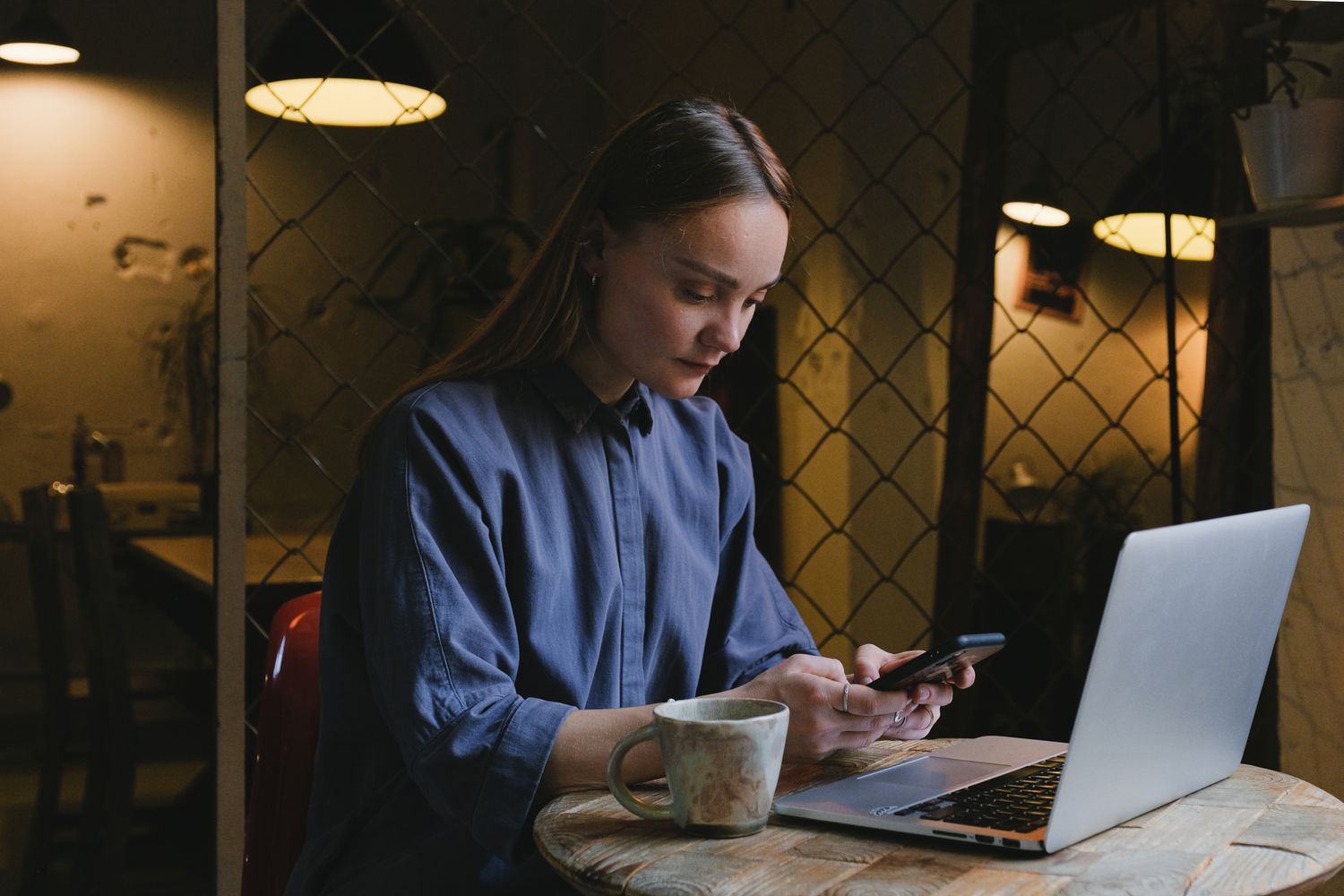 Woman managing guest messages on her phone at a cafe table