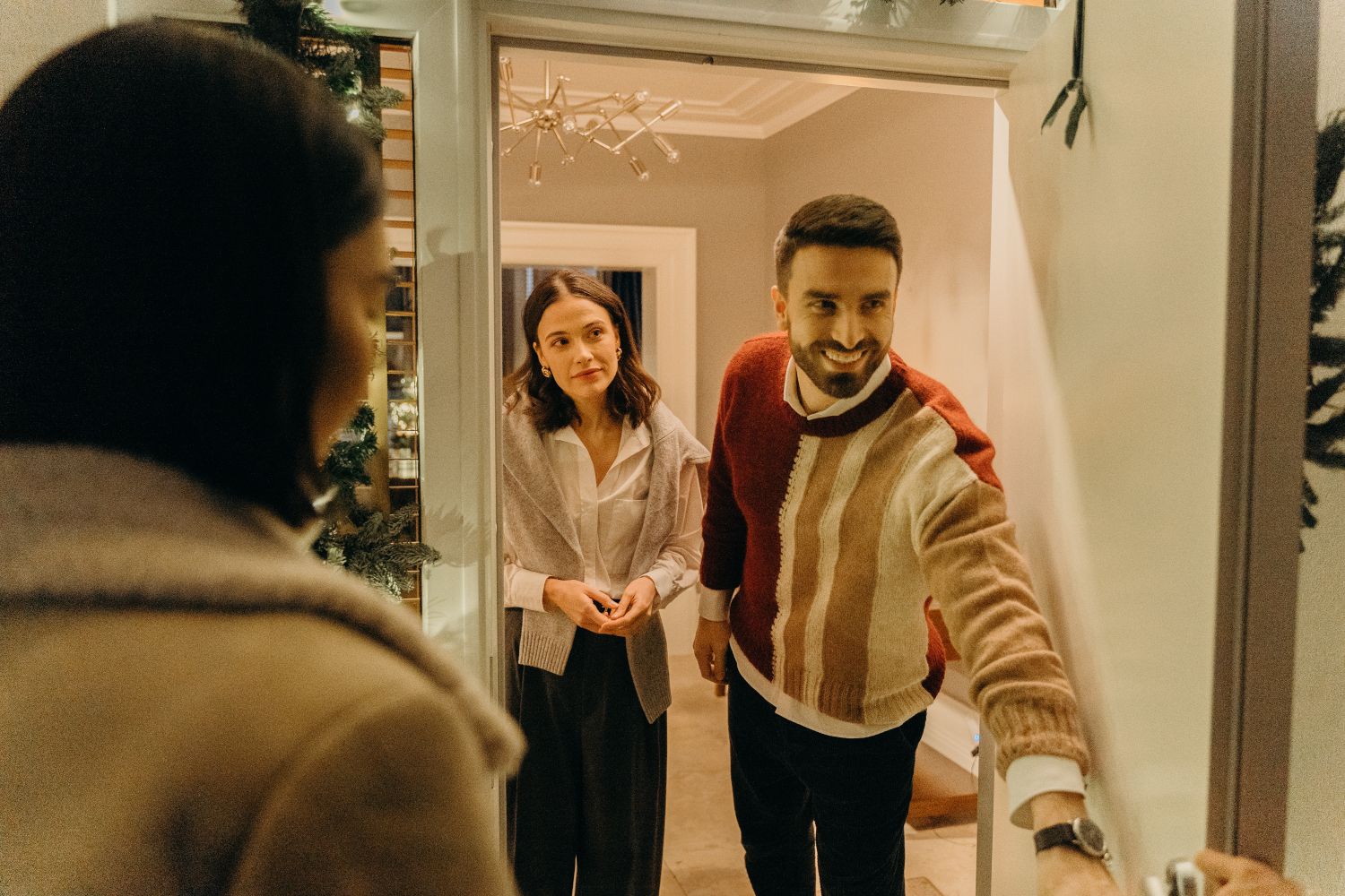 Smiling host opening the door to welcome arriving guests