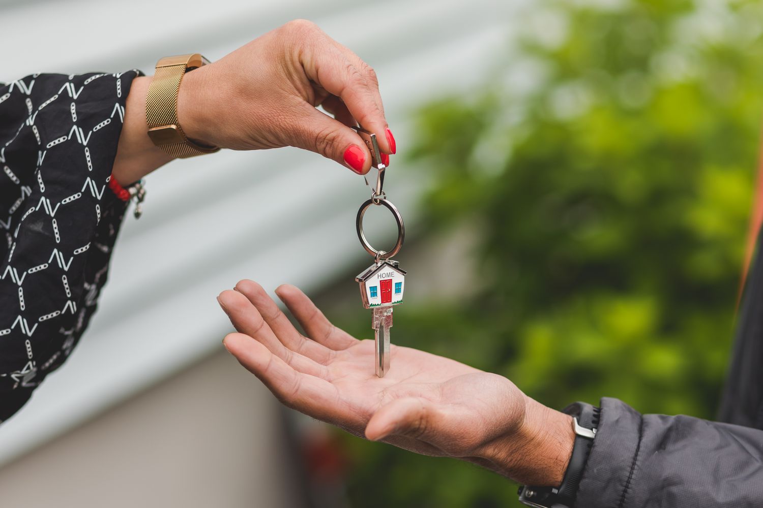 Hand passing a house key with a keychain to another person