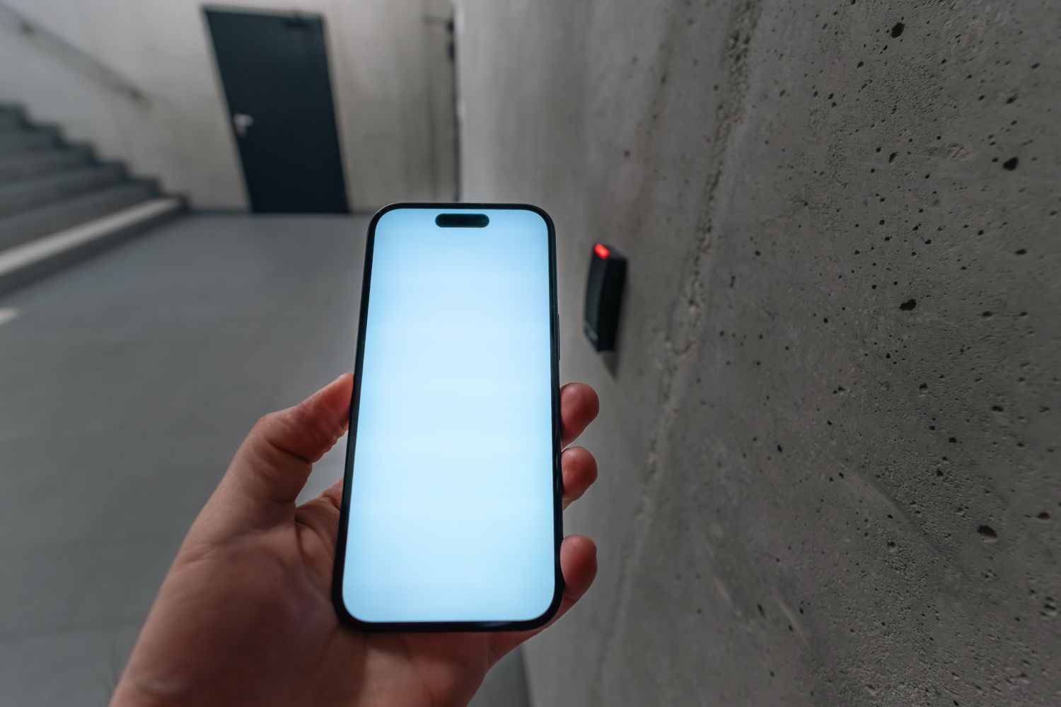 Smartphone held up to a door access reader in a modern building